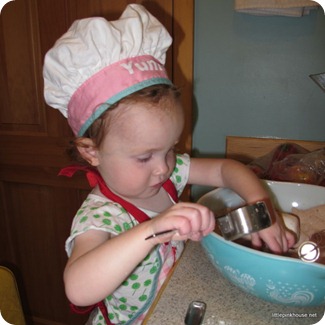 Mary cooking in big sister's apron